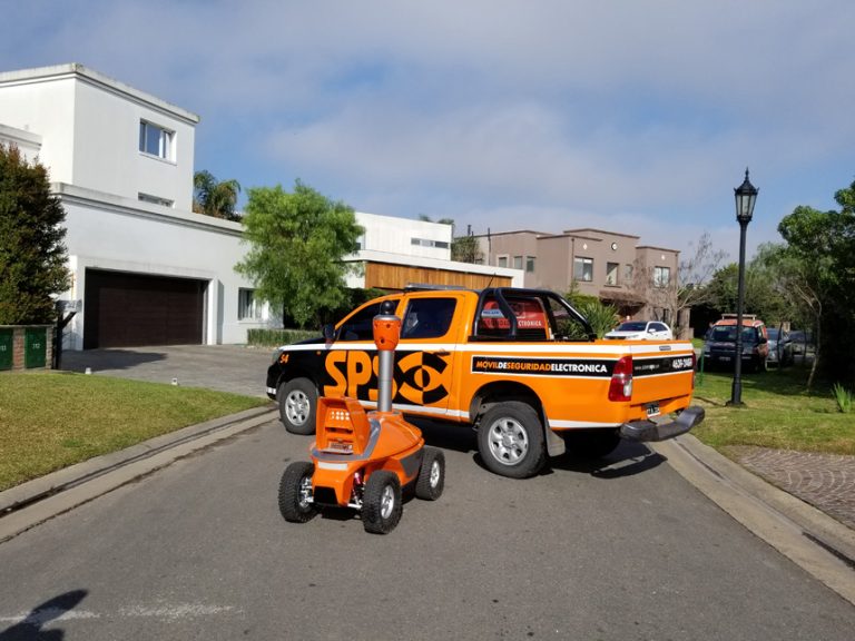 Охранный робот SMP Robotics рядом с автомобилем службы безопасности в Аргентине